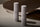 Two tall grey bottles on a curved stone surface