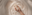 Hand holding a cream tube over a swirl of white cream