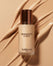 Bottle of liquid foundation beside smooth swatches of the formula