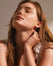 Woman applying serum to her neck with a glass dropper