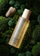 Glass bottle of golden oil resting on moss